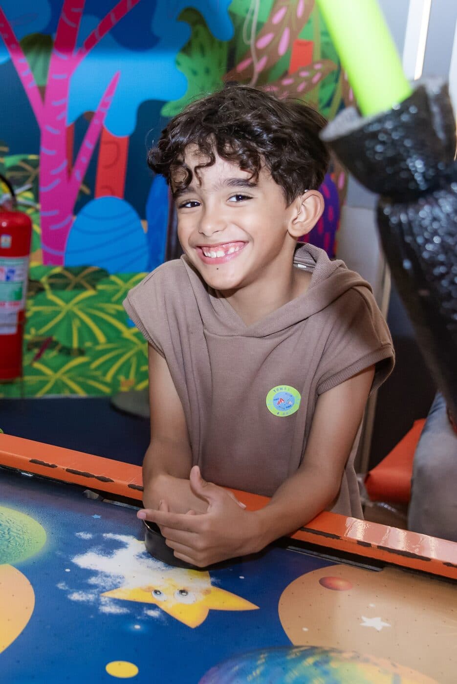 Menino sorrindo apoiado em uma mesa de jogos em festa infantil